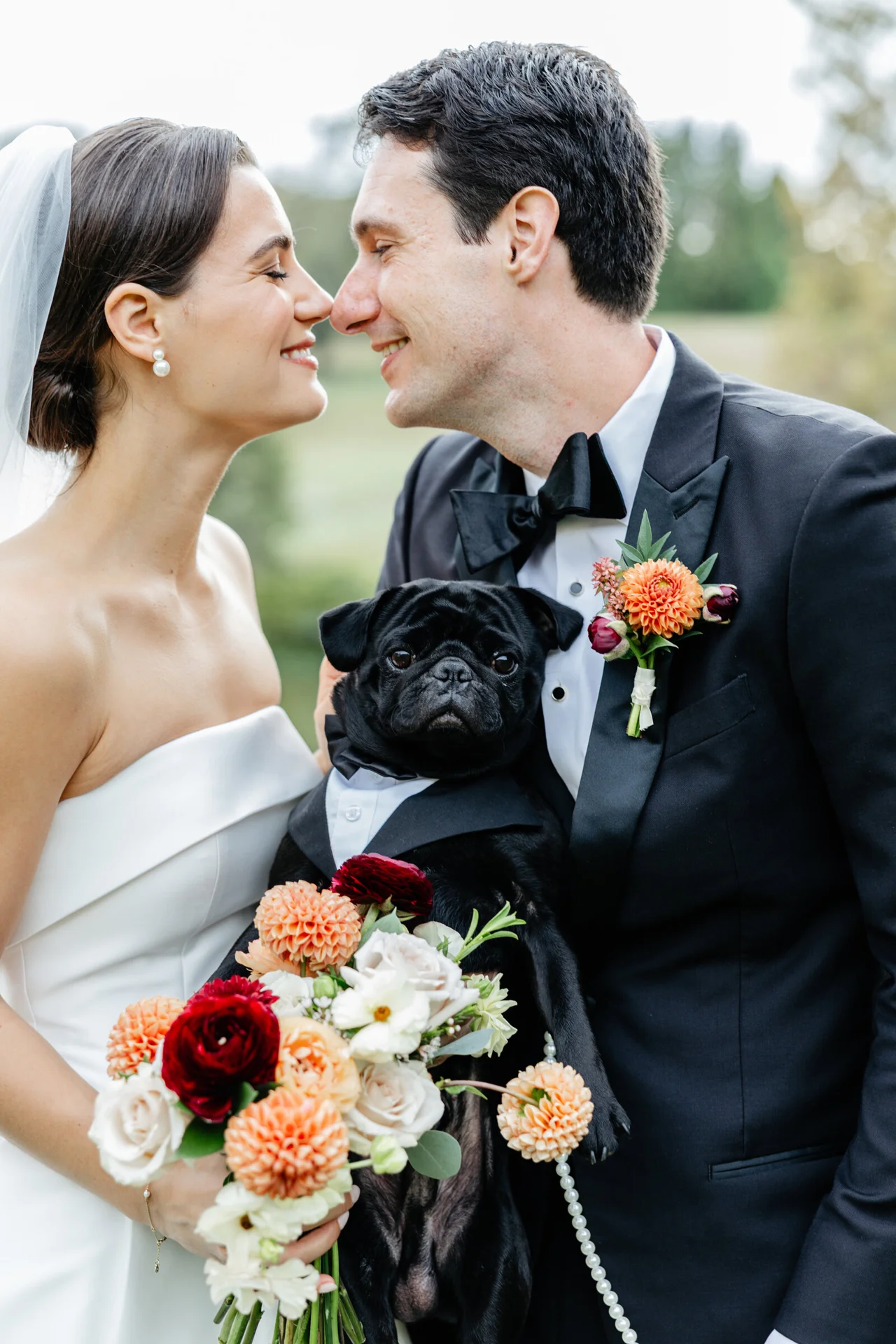 Bride and groom holding a black dog