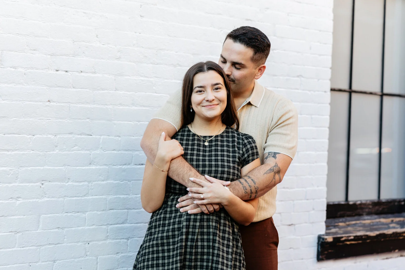 Couple embracing in front of a white brick wall