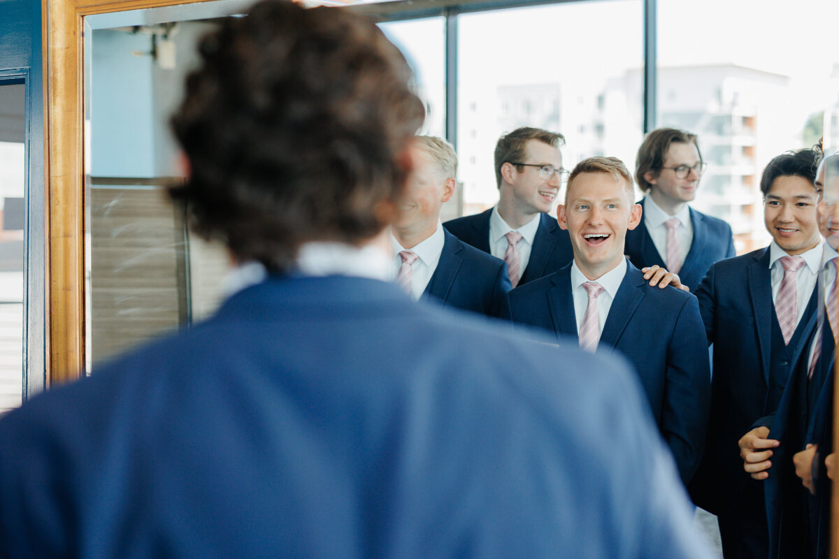 Groom facing his smiling groomsmen in blue suits