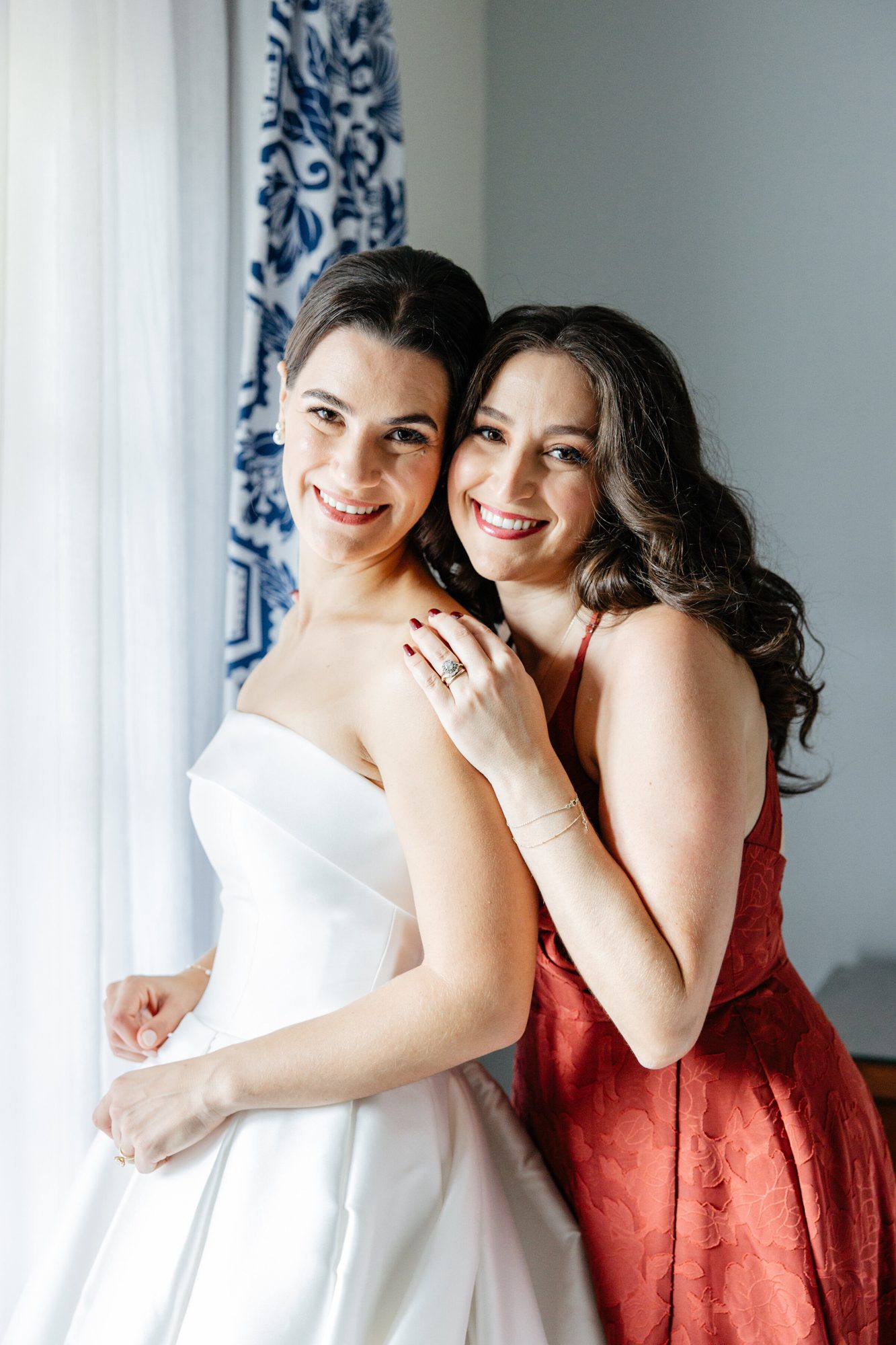 Bride embracing her sister by a window at Boars Head Resort