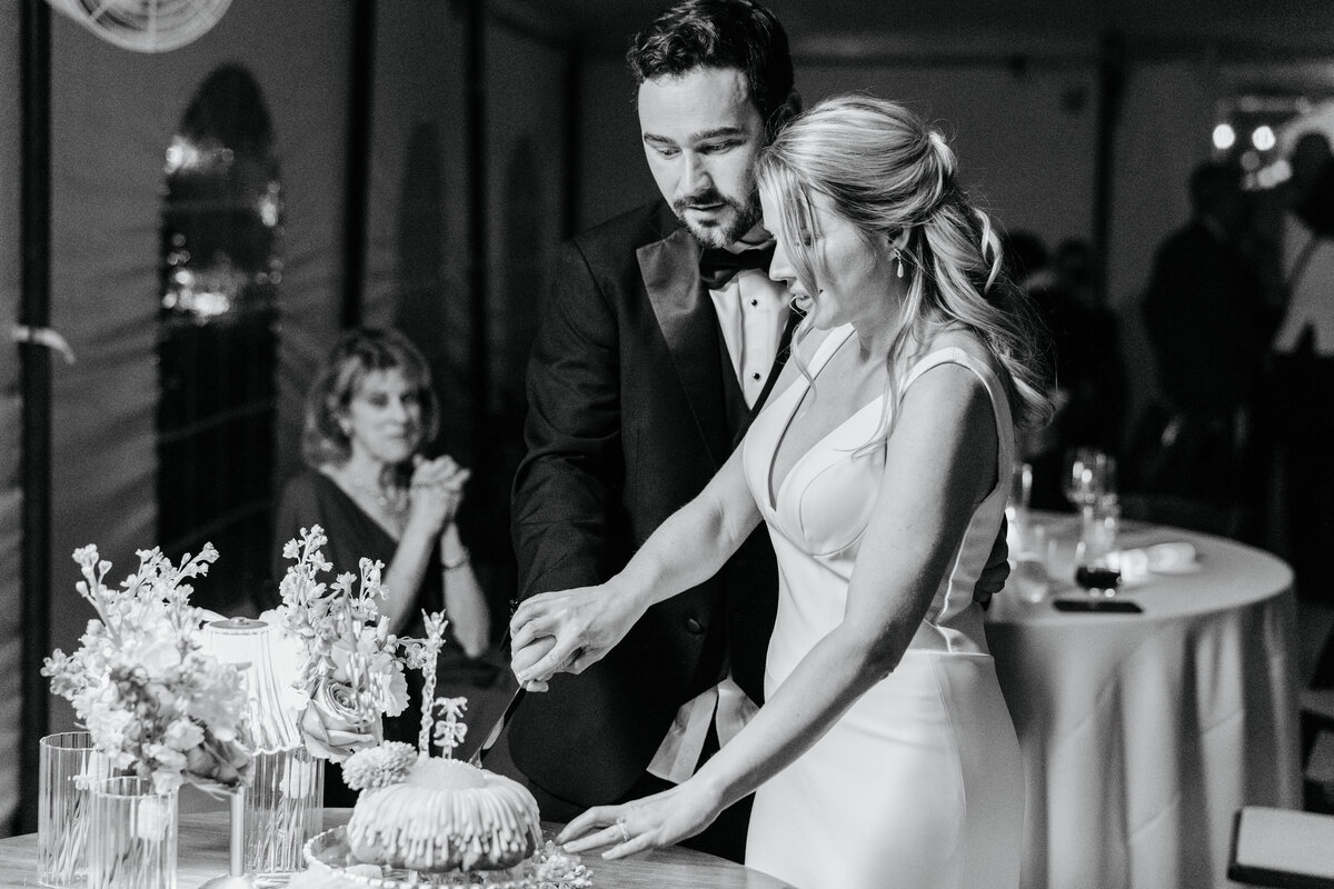Black-and-white photograph of newlyweds cutting their wedding cake