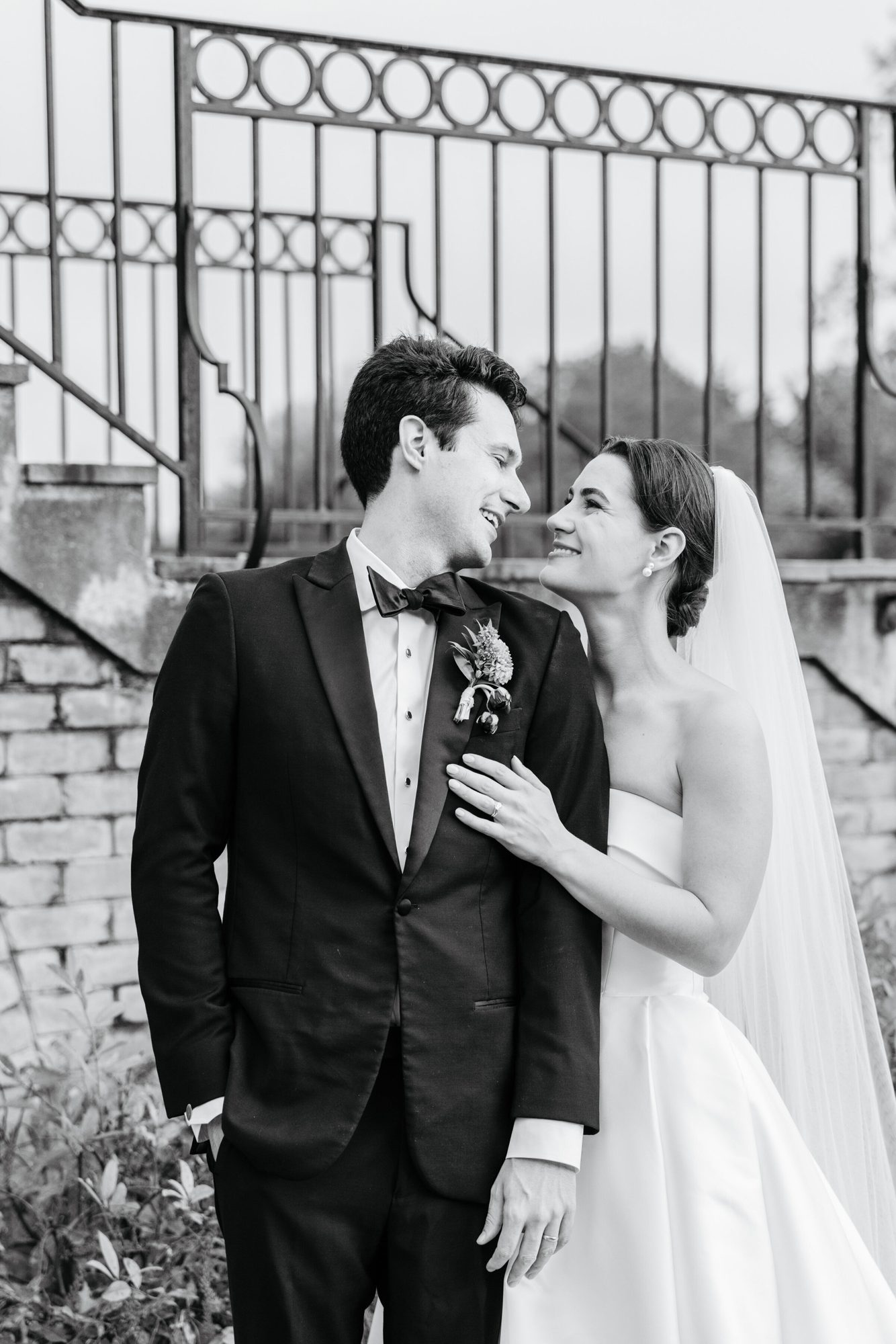 Black-and-white portrait of the couple by an iron railing at Boars Head Resort