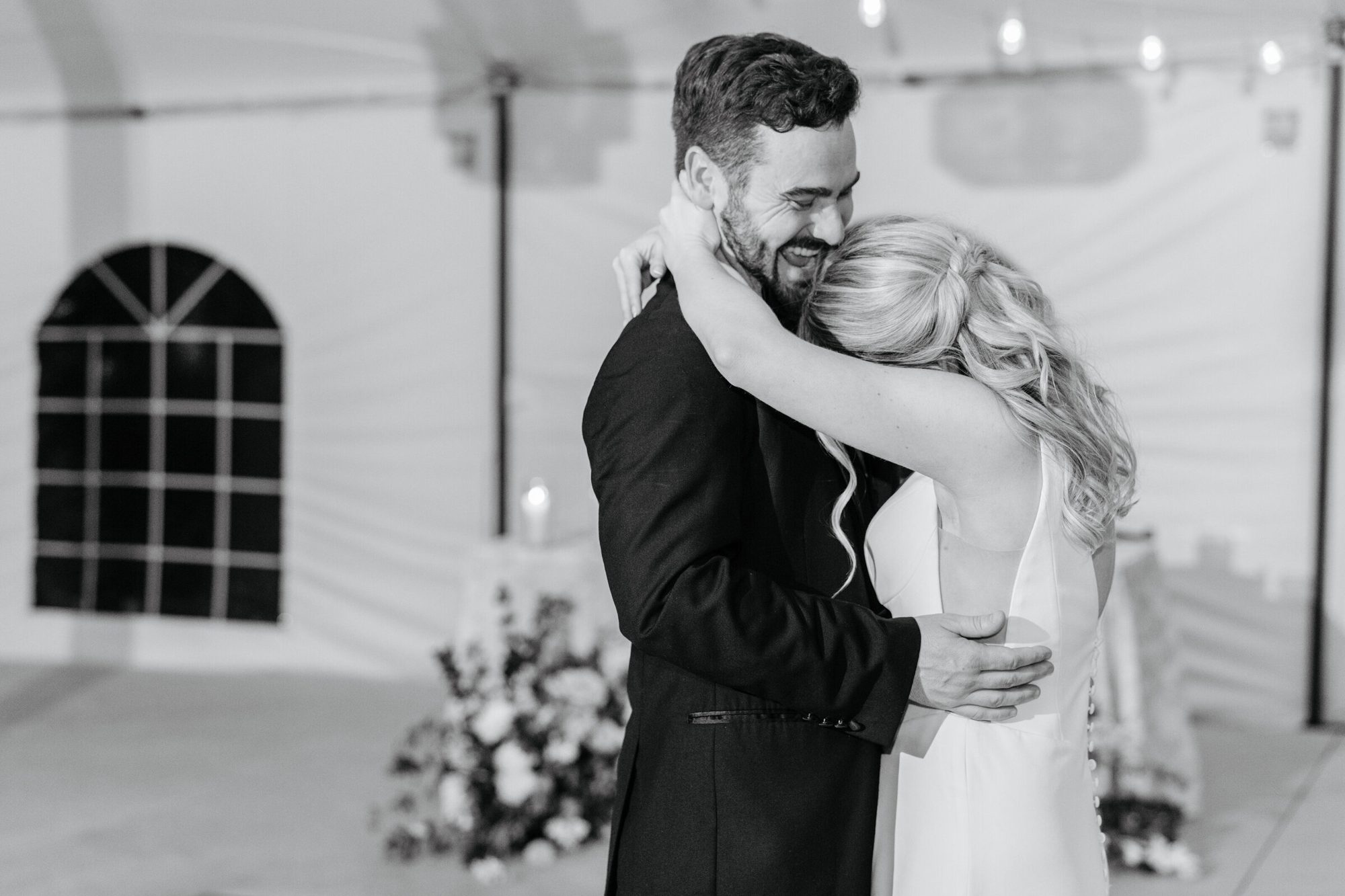 Black-and-white photo of the couple embracing in the tent at Historic Whitewood