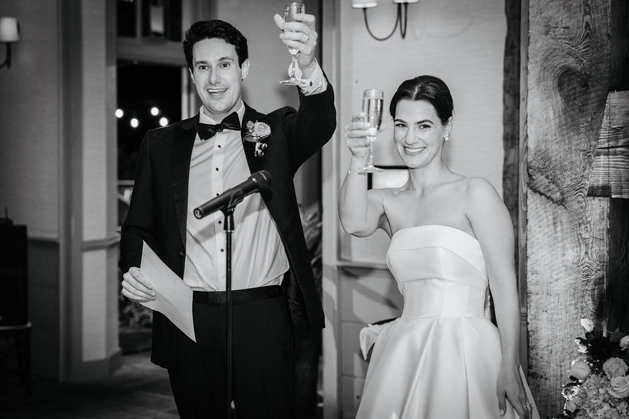 Black-and-white photo of the couple raising glasses during toasts at Boars Head Resort