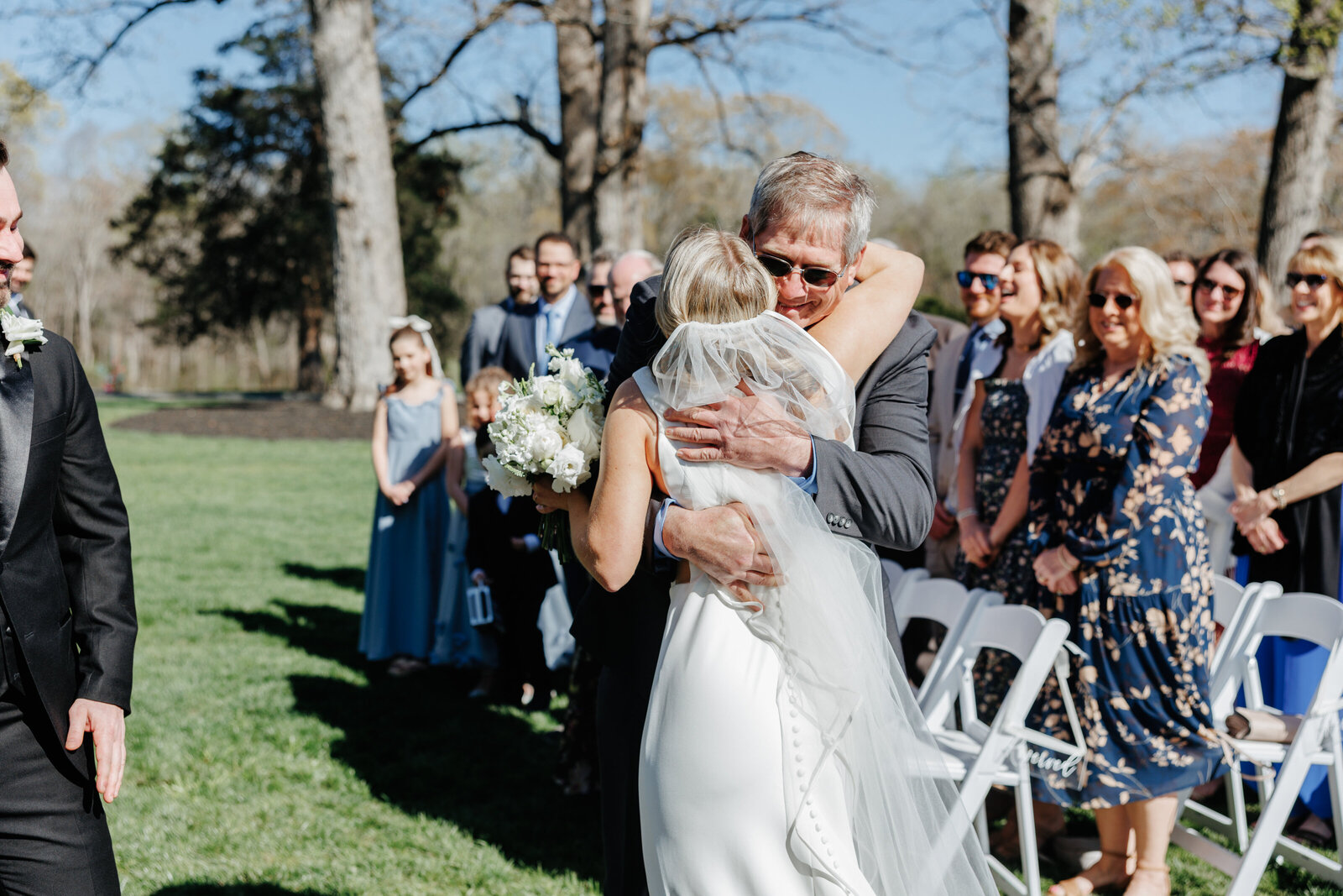 Bride embracing an older guest at an outdoor wedding ceremony