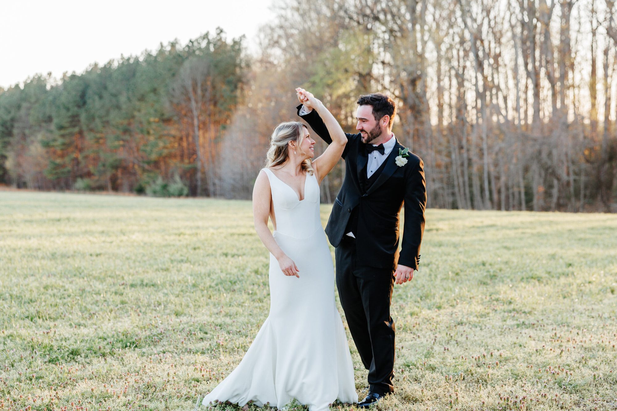 Groom twirling the bride in a field at Historic Whitewood