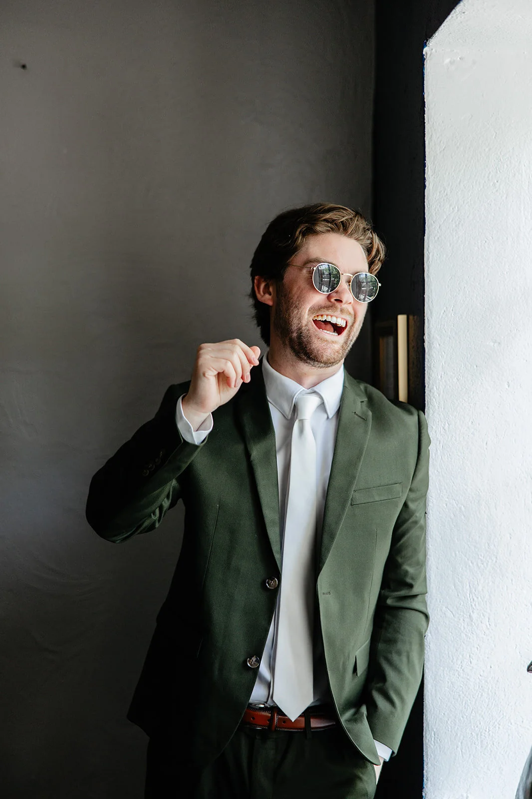 Groom in sunglasses laughing in a doorway