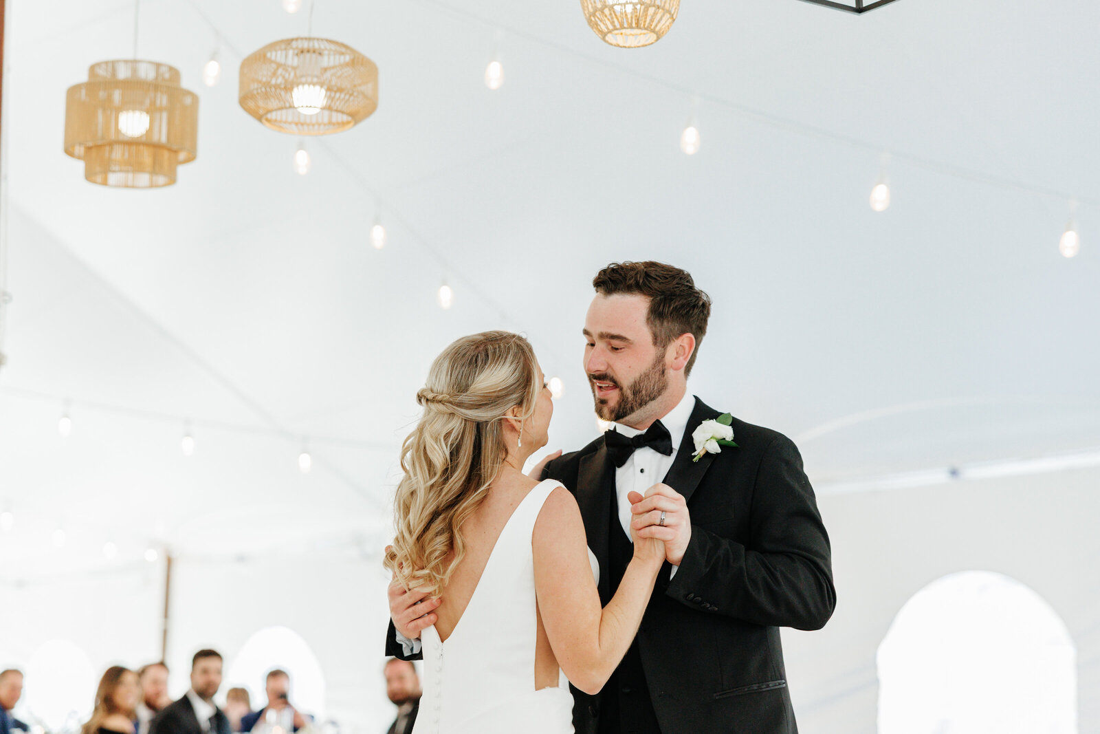 Bride and groom sharing their first dance beneath a white reception tent