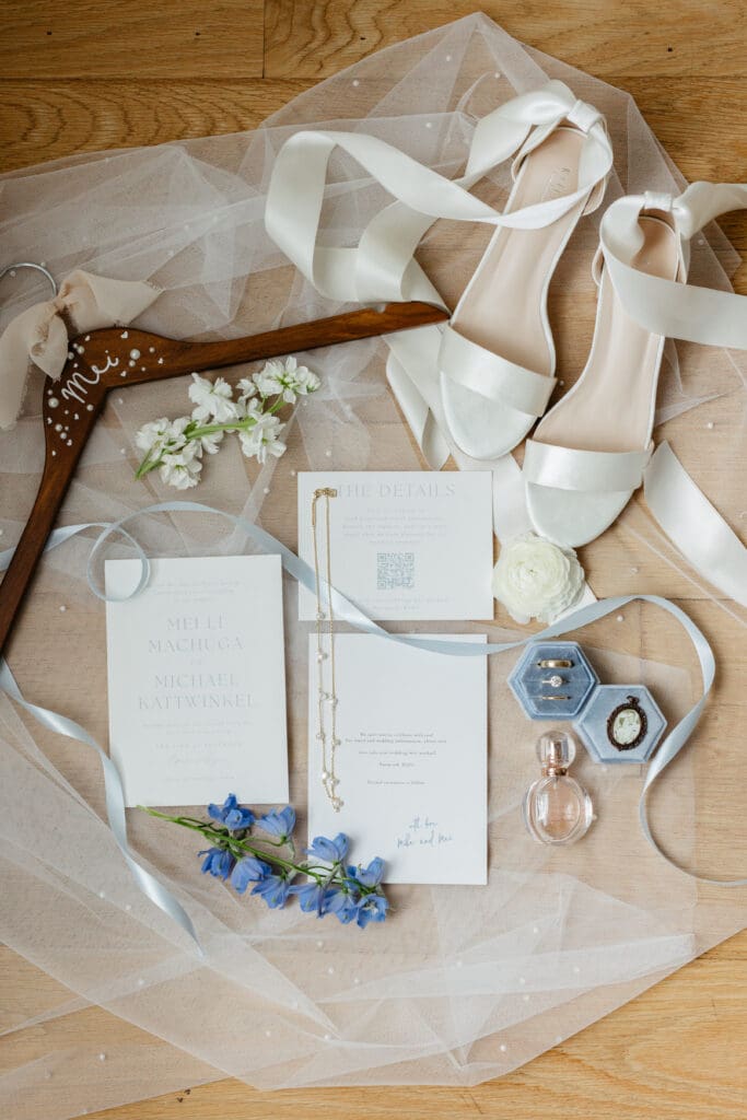 A flat lay of wedding rings, invitation suite, and bridal shoes arranged as part of a wedding detail photos checklist.