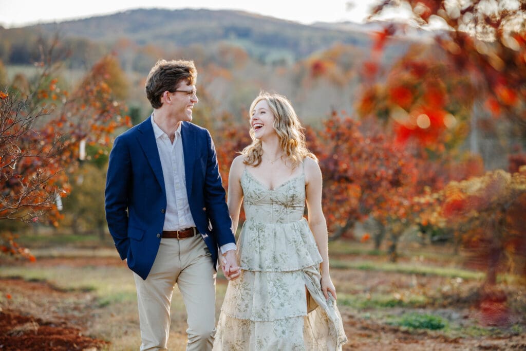 A couple standing among colorful fall foliage at a Virginia venue, showing off gorgeous fall wedding photo ideas.